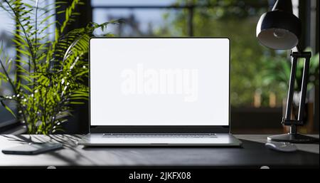 Laptop with blank frameless screen mockup template on the table in industrial office loft interior - front view Stock Photo