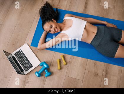 A young woman rests on her mat after home online fitness workout Stock Photo