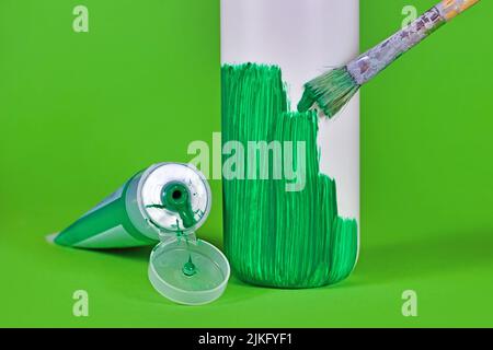 Concept for greenwashing with white plastic bottle being painted green Stock Photo