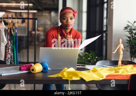 Portrait of confident african american fashion designer at desk in studio office Stock Photo