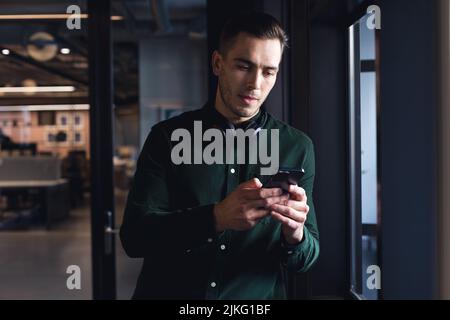 Caucasian young businessman text messaging through smart phone in creative office Stock Photo