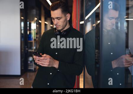 Caucasian young businessman using internet in smart phone at creative office Stock Photo