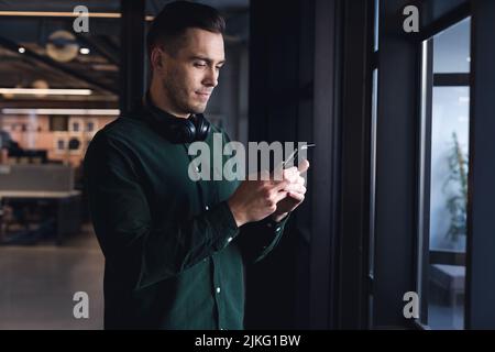 Caucasian young businessman text messaging through mobile phone in creative office Stock Photo