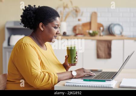 Portrait of smiling black woman drinking smoothie side view Stock Photo