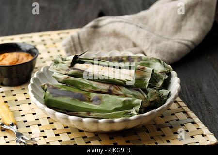 Grilled Otak otak, Indonesian Fish Cake Wrapped with Banana Leaf and Grill. Served with Peanut SAuce or Sweet and Savory Red Spicy Sauce Stock Photo