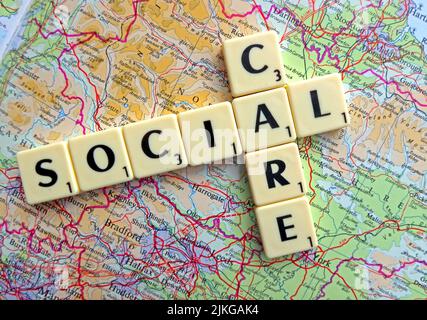Social Care spelled out in Scrabble letters on a map of England Stock Photo