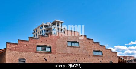 Brick wall of historic building with modern building on the back Stock Photo