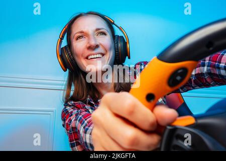 Portrait with console steering wheel of a laughing gamer woman Stock Photo