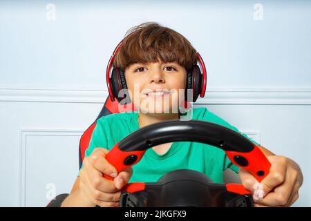Happy boy in headphones with steering wheel play race game Stock Photo