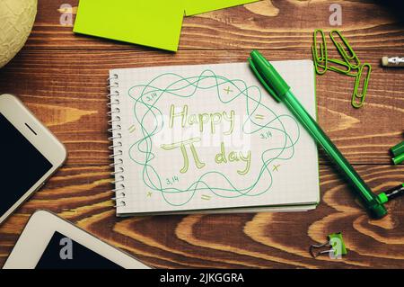 Notebook with text HAPPY PI DAY and stationery on wooden background Stock Photo