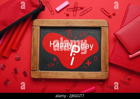 Chalkboard with text HAPPY PI DAY and stationery on red background Stock Photo