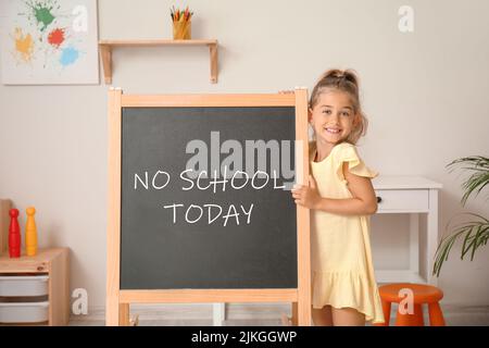 Happy little girl and chalkboard with written text NO SCHOOL TODAY in classroom Stock Photo