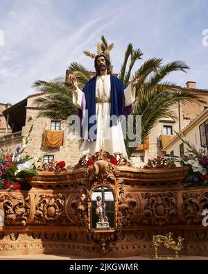 A vertical shot of Jesus Christ sculpture against palm trees during  Passion Week in Plasencia. Spain. Stock Photo