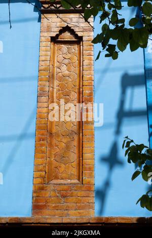 A vertical shot of a facade detail from brick with beautiful carvings on a blue wall Stock Photo