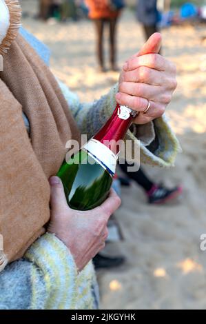 A man opening a bottle of champagne in the park Stock Photo