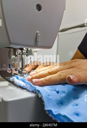 A closeup shot of seamstress hands working on a sewing machine Stock Photo