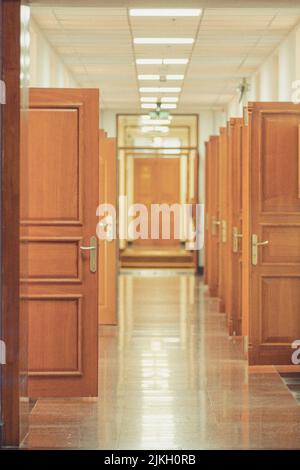 A vertical shot of open wooden doors in a long corridor Stock Photo