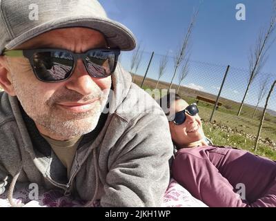 Middle-aged couple in sunglasses resting on the grass Stock Photo