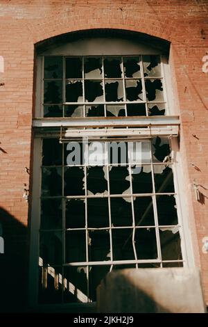 A vertical shot of an old abandoned window with shattered glass Stock Photo