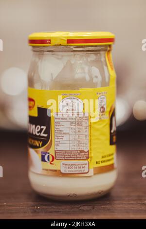 A vertical shot of a Polish Winiary brand mayonnaise in a glass jar on a wooden table Stock Photo