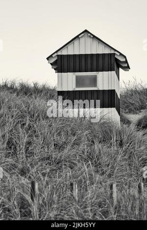 A vertical grayscale shot of a little lighthouse on the North Sea coast in Denmark Stock Photo
