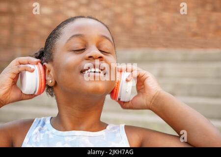 close-up portrait of a happy girl listening to music on headphones with closed eyes Stock Photo
