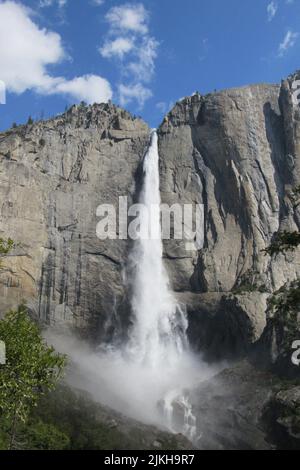 A vertical shot of a beautiful waterfall flowing through the mountains in Yosemite National Park, USA Stock Photo