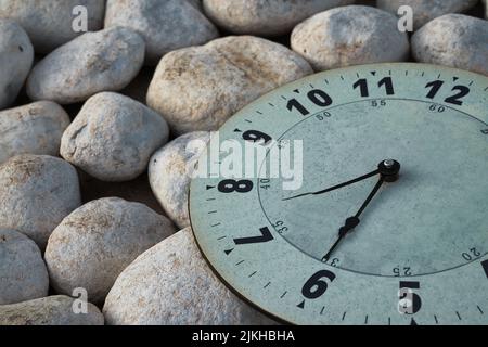 White wall clock on a background of natural stones at 6:30. Concept of hour, time, schedule. Wake up in the morning, get up early. Stock Photo