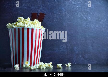 A bucket of popcorn with film strips on a blue background with copy space Stock Photo