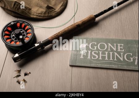 Gone fishing sign, fly fishing tackle on a light wood background Stock Photo