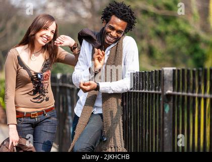 Park Life: sharing a moment. A candid moment from a young mixed race couple relaxing in a park. From a series of images with the same characters. Stock Photo
