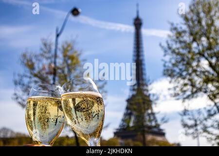 A shallow focus shot of two glasses of champagne against the Eiffel Tower background Stock Photo