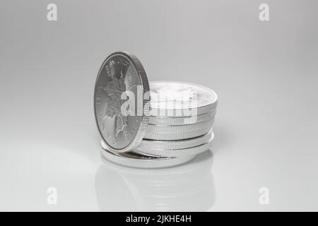 A stack of 1oz Silver Canadian Maple Leaf on gray background Stock Photo