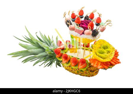 Pina colada cocktail in pineapple shell with sliced exotic fruits and candies isolated on white background. Stock Photo