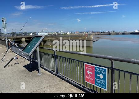 Fishing, Cardiff Bay Barrage on wrong side of no fishing sign. Cardiff, Wales. Stock Photo