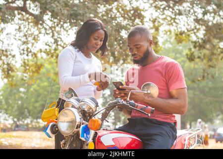 african man and woman sharing content from their phones Stock Photo