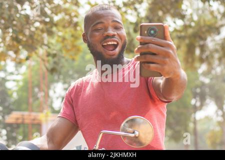 okada rider looks at his phone feeling excited Stock Photo