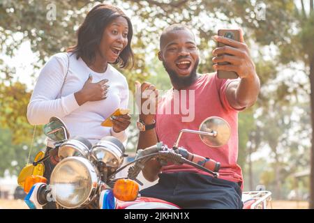 african man and woman look at phone excitedly Stock Photo
