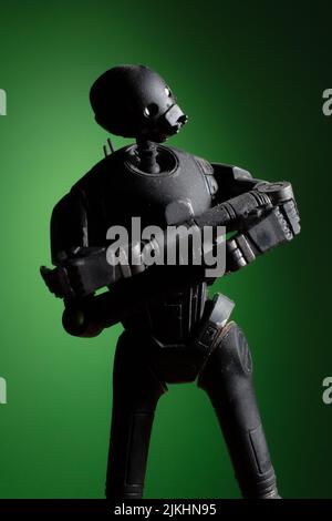 A vertical shot of a futuristic black plastic toy figurine on a green background Stock Photo