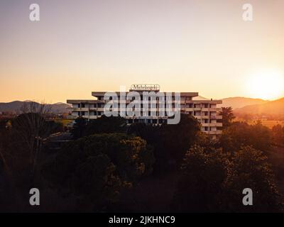 An abandoned Michelangelo hotel building on a hill surrounded by trees in the sunset. Stock Photo