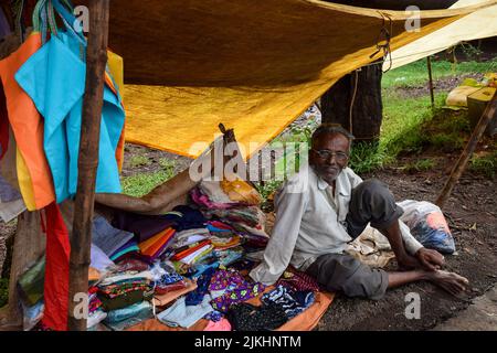 Kolhapur, India- September 13th 2019; Stock photo of 60 to 70 old Indian man sitting on street and selling cloths in the weekly market of Indian villa Stock Photo