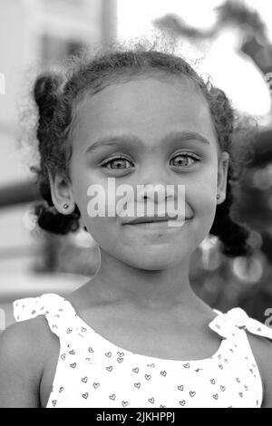 a vertical shot of small girl smiling in grayscale Stock Photo