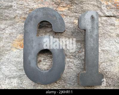 A beautiful shot of a house number 61 ade with stone on a granite rock Stock Photo