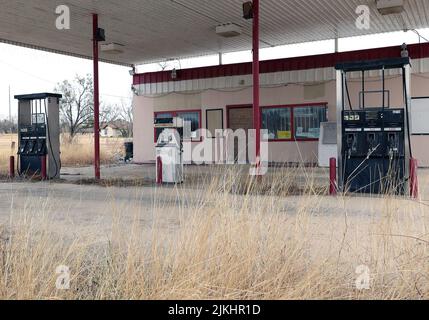 An old abandoned gas station in the small town of Lytle with over grown weeds and old pumps, Texas, United States Stock Photo