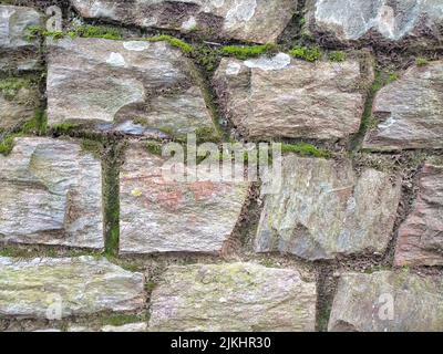 A beautiful shot of a rough grey irregular mossy stone wall Stock Photo