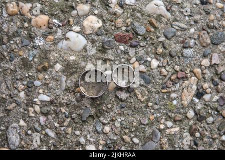 A closeup shot of two wedding rings on the textured ground Stock Photo