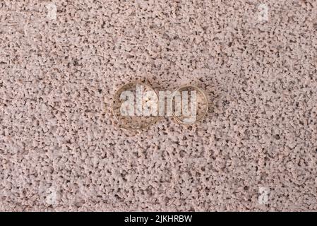 A closeup shot of two wedding rings on the textured ground Stock Photo