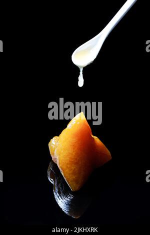 A closeup shot of a White chocolate sauce spoon falling on Zongzi traditional Chinese with black background Stock Photo