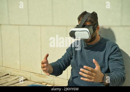 Smiling man using virtual reality (VR) glasses outdoors on a sunny day Stock Photo