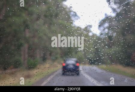 A driving car in wet weather with raindrops on windscreen Stock Photo